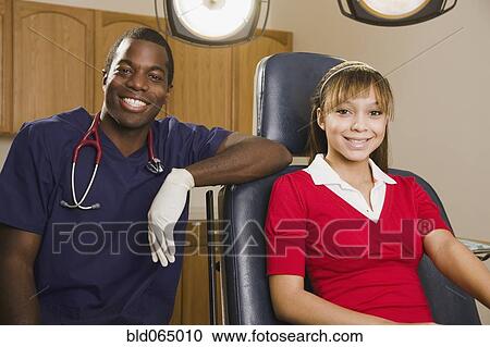 Stock Image - African dentist with teenage patient. Fotosearch