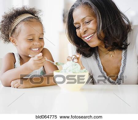 Stock Photography - African grandmother and granddaughter sharing ice cream. Fotosearch