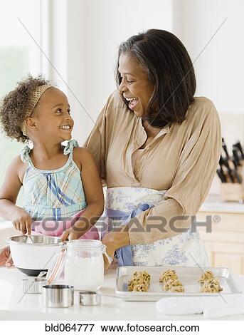 Stock Photo - African grandmother baking cookies with granddaughter. Fotosearch
