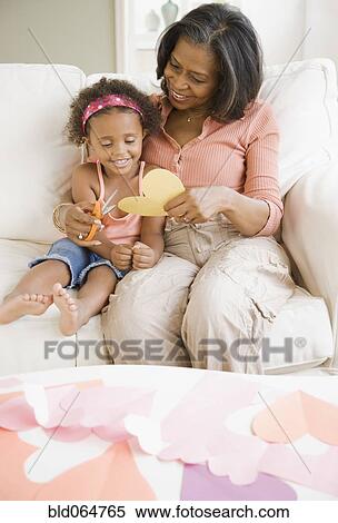 Stock Photography - African grandmother cutting out heart-shape with granddaughter. Fotosearch