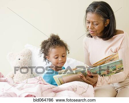 Stock Photograph - African grandmother reading granddaughter a bedtime story. Fotosearch