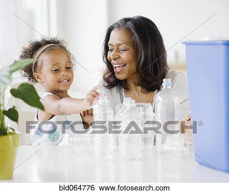 Stock Photograph - African grandmother teaching granddaughter how to recycle. Fotosearch