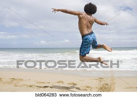 African man at beach jumping in mid-air View Large Photo Image Stock Image - African man at beach jumping in mid-air. Fotosearch