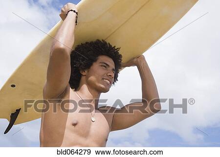 Stock Photo - African man at beach with surfboard. Fotosearch