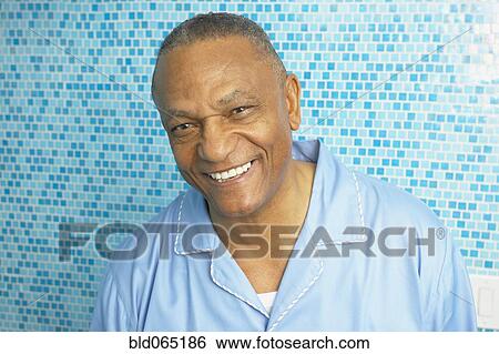 Stock Photograph - African man in pajamas smiling in bathroom. Fotosearch