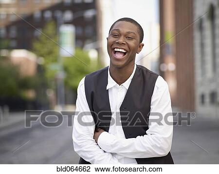 Stock Image - African man laughing in urban setting. Fotosearch