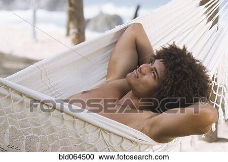 Stock Image - African man laying in hammock. Fotosearch
