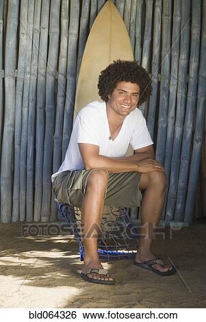 Stock Photograph - African man outdoors with surfboard. Fotosearch