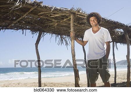 Stock Image - African man relaxing at beach. Fotosearch