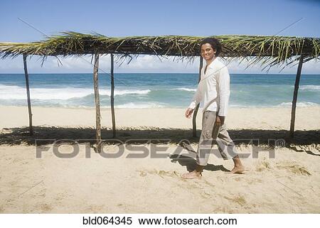 Stock Photography - African man walking at beach. Fotosearch