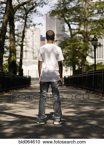 Stock Image - African teenage boy standing in urban park. Fotosearch