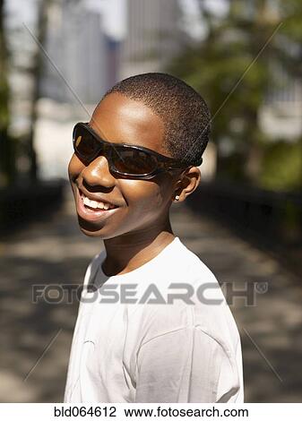 Stock Image - African teenage boy standing in urban park. Fotosearch