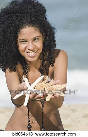 Stock Image - African woman holding out starfish. Fotosearch