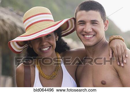 Stock Photograph - African woman hugging boyfriend at beach. Fotosearch