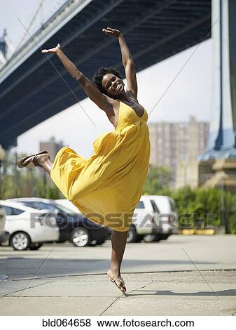 Stock Photo - African woman jumping in mid-air in urban setting. Fotosearch