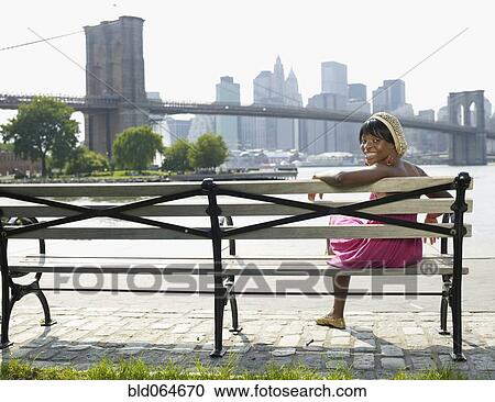 African woman sitting on bench at urban waterfront View Large Photo Image Stock Image - African woman sitting on bench at urban waterfront. Fotosearch