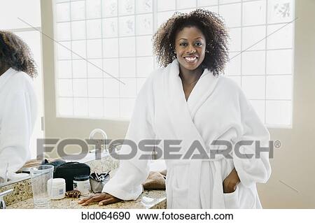 Stock Image - African woman wearing bathrobe in bathroom. Fotosearch
