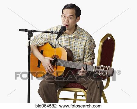 Stock Image - Asian man playing guitar and singing. Fotosearch