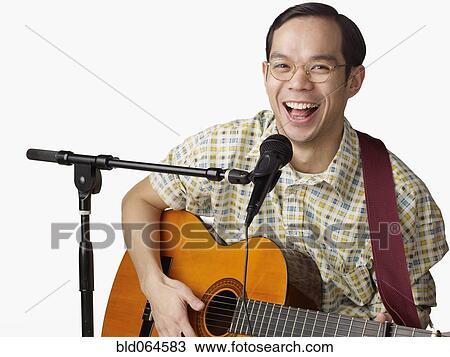 Stock Image - Asian man playing guitar and singing. Fotosearch
