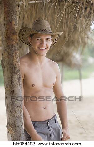 Stock Image - Bare chested Hispanic man in cowboy hat. Fotosearch