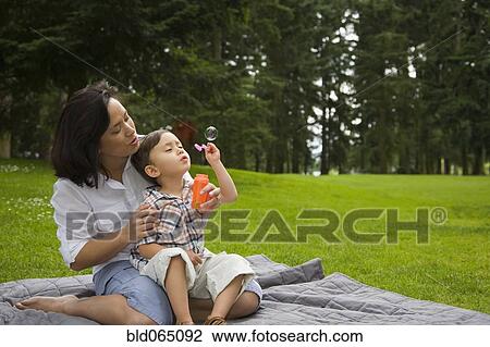 Boy blowing bubbles in park with mother View Large Photo Image Stock Image - Boy blowing bubbles in park with mother. Fotosearch