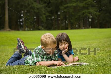 Stock Photograph - Brother and sister reading story book in park. Fotosearch