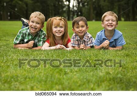 Picture - Children laying in grass in park. Fotosearch
