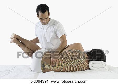 Stock Image - Chiropractor adjusting man’s back. Fotosearch