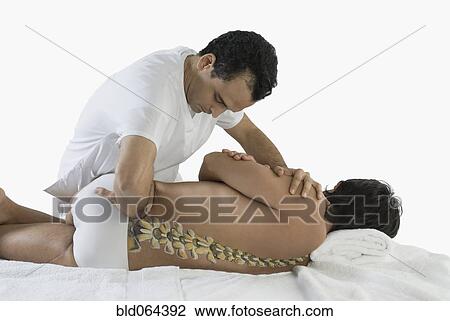 Stock Image - Chiropractor adjusting man’s back. Fotosearch
