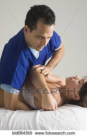 Stock Photography - Chiropractor adjusting woman’s back. Fotosearch