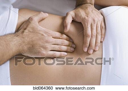 Stock Image - Chiropractor adjusting woman’s spine. Fotosearch