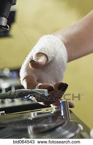 Stock Image - Close up of woman starting record player. Fotosearch