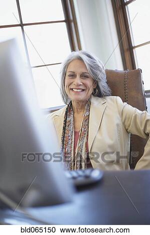 Confident businesswoman working on computer at desk View Large Photo Image Stock Image - Confident businesswoman working on computer at desk. Fotosearch