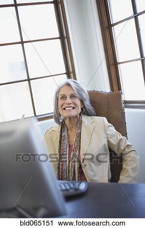 Confident businesswoman working on computer at desk View Large Photo Image Stock Image - Confident businesswoman working on computer at desk. Fotosearch