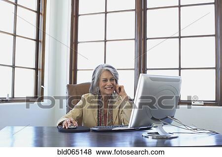 Stock Photo - Confident businesswoman working on computer at desk. Fotosearch