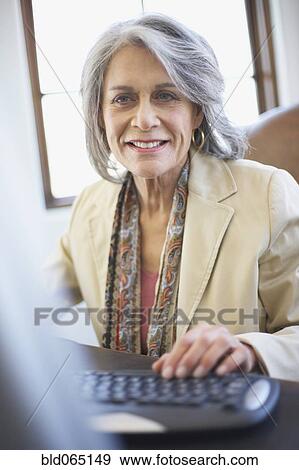 Confident businesswoman working on computer at desk View Large Photo Image Stock Photo - Confident businesswoman working on computer at desk. Fotosearch