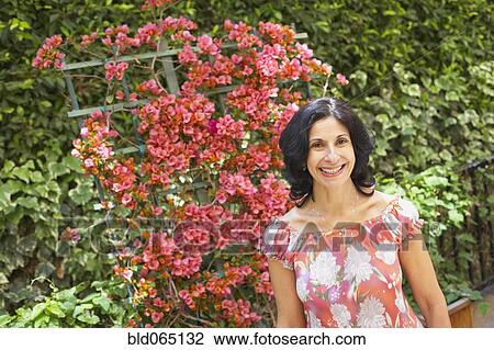 Stock Image - Confident Middle Eastern woman standing in garden. Fotosearch