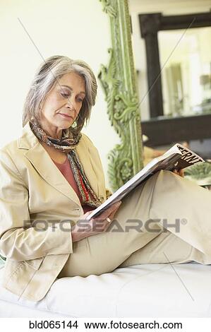 Picture - Confident woman relaxing and reading magazine. Fotosearch