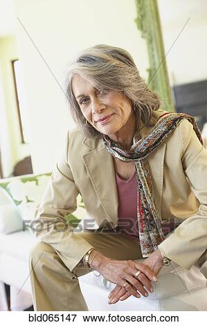 Stock Photo - Confident woman sitting in living room. Fotosearch