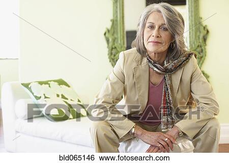 Stock Photograph - Confident woman sitting in living room. Fotosearch