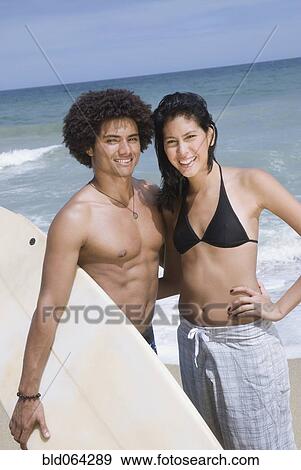 Stock Photo - Couple with surfboard at beach. Fotosearch