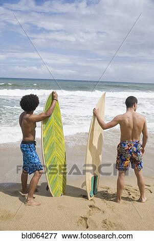 Stock Photo - Friends at beach with surfboards. Fotosearch