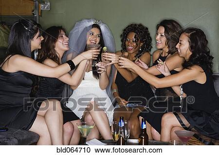 Stock Image - Friends drinking cocktails with bride in nightclub. Fotosearch