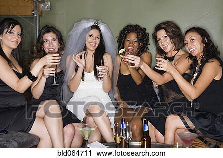Stock Image - Friends drinking cocktails with bride in nightclub. Fotosearch