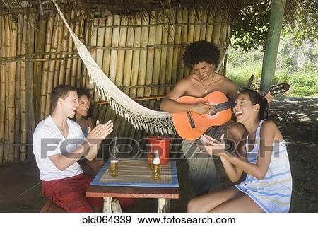 Stock Photo - Friends listening to man play guitar. Fotosearch