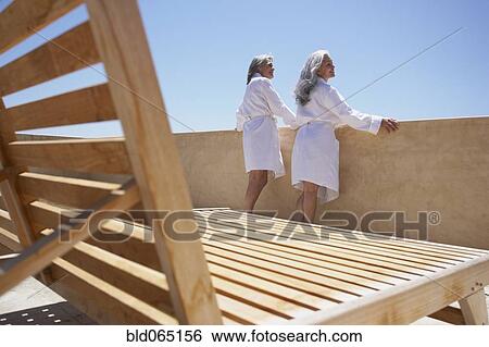 Friends looking over balcony at resort View Large Photo Image Stock Photograph - Friends looking over balcony at resort. Fotosearch