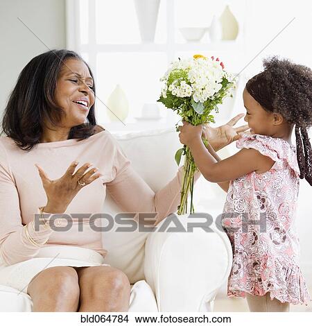 Picture - Granddaughter giving African grandmother bouquet of flowers. Fotosearch