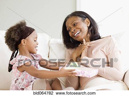 Stock Image - Granddaughter giving African grandmother gift. Fotosearch