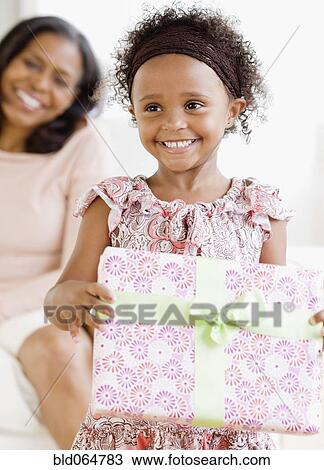 Stock Image - Granddaughter giving African grandmother gift. Fotosearch