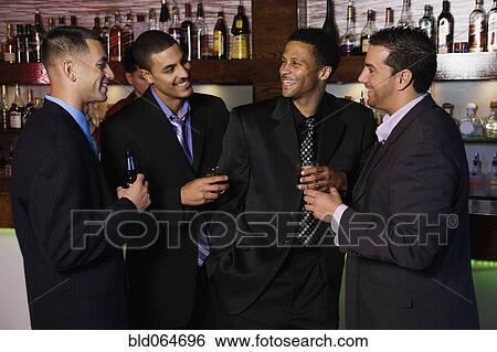 Stock Photograph - Group of multi-ethnic businessmen drinking in bar. Fotosearch